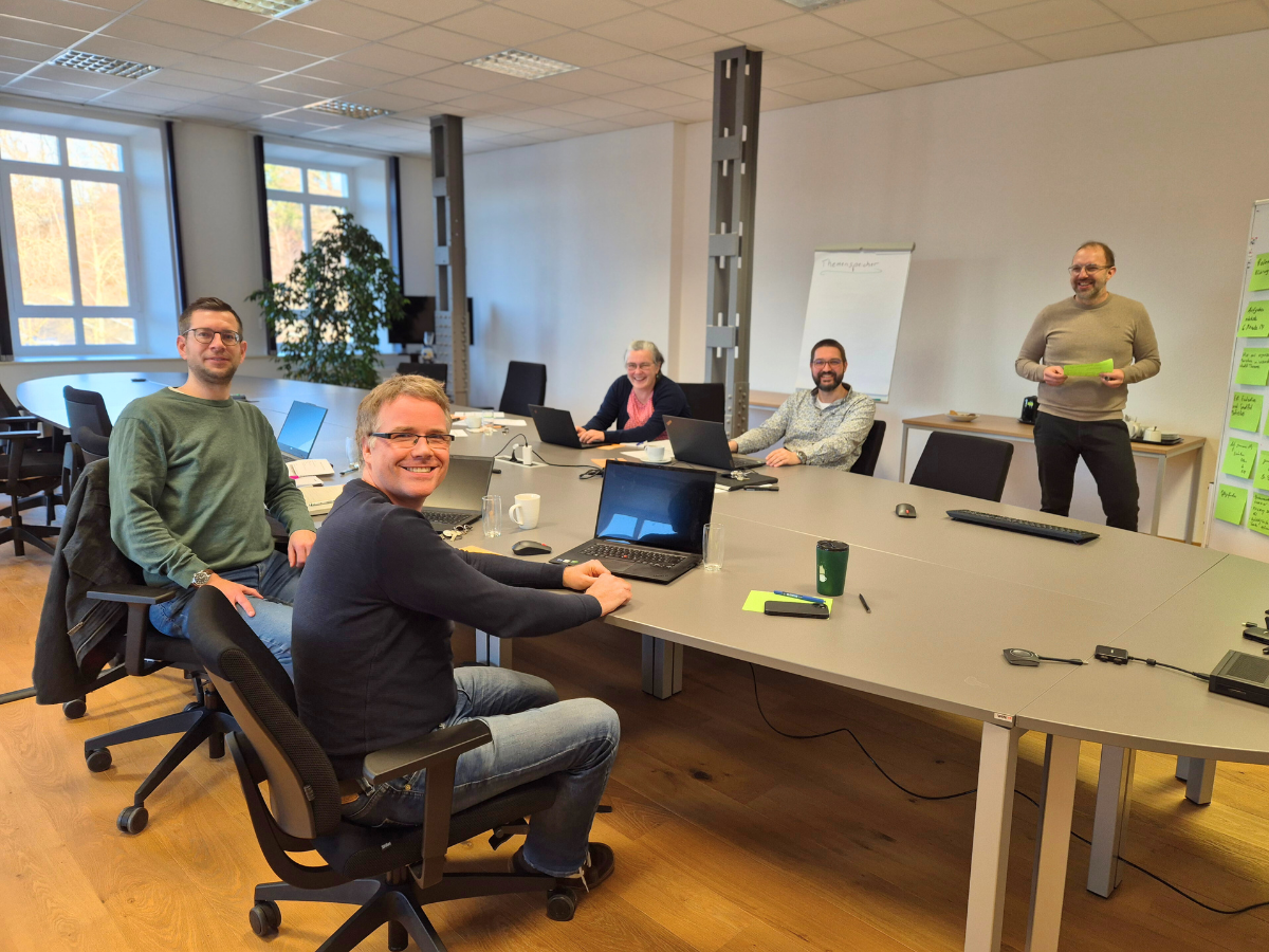 Mitarbeiter von KiPf und FiPtec sitzen am Konferenztisch mit Laptops u