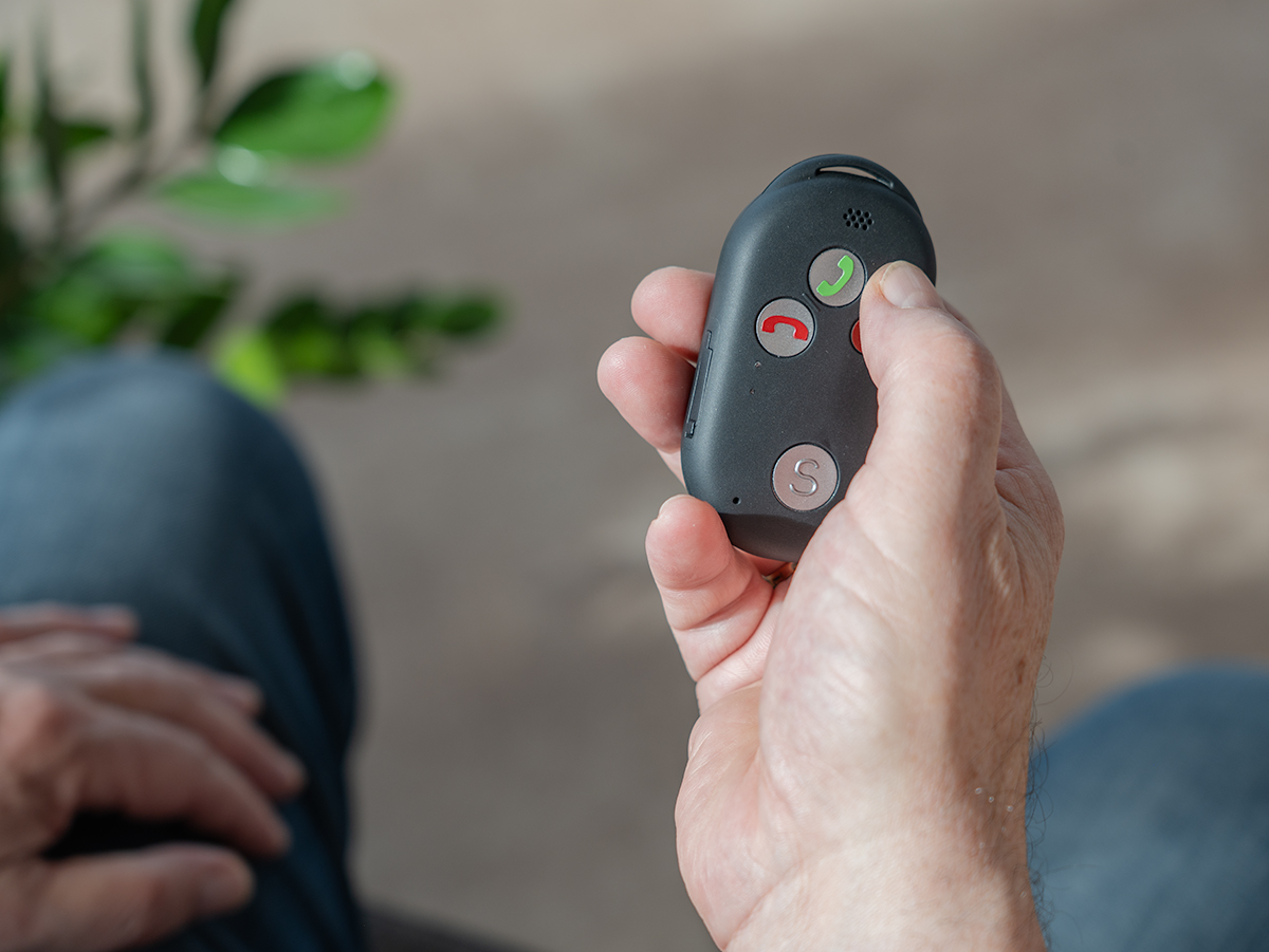 Ein Senior hält ein Pushphone in seiner Hand.
