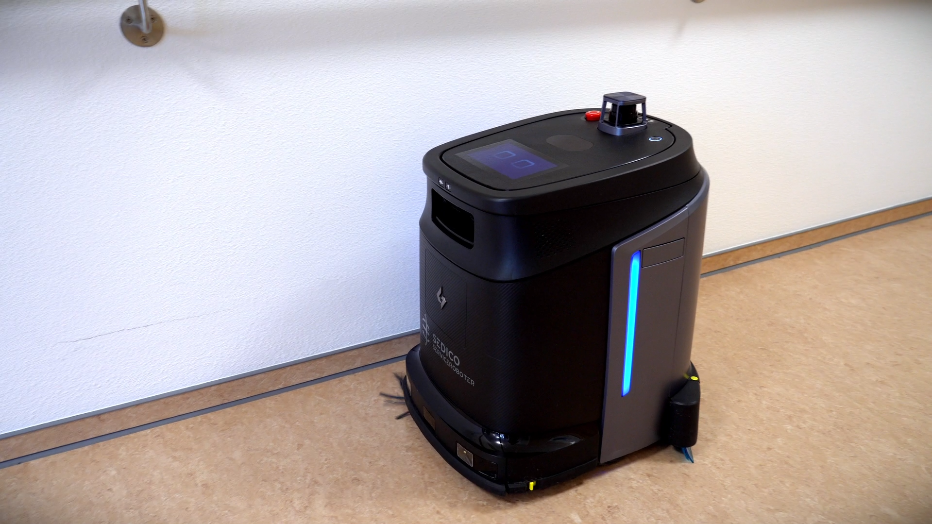 Schwarzer kniehoher Reinigungsroboter schräg von oben wischt Boden