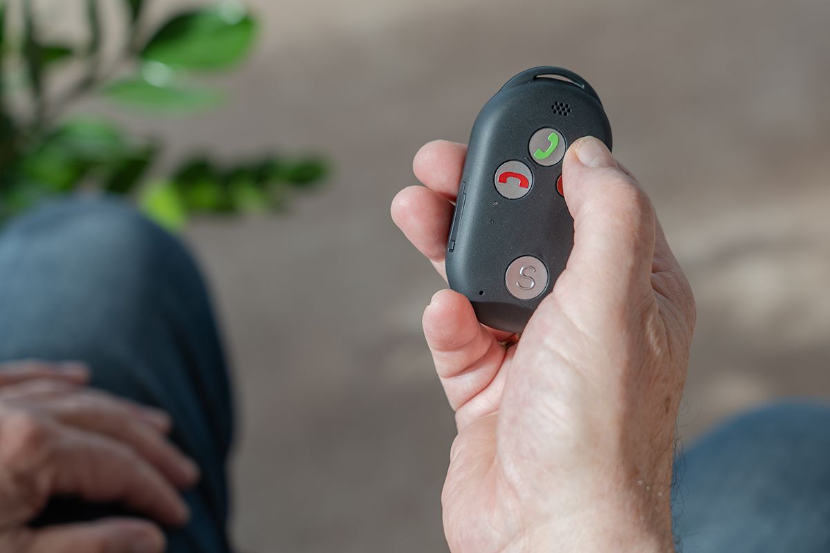 Ein Senior hält ein Pushphone in seiner Hand.