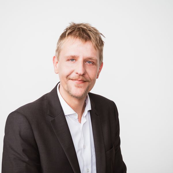 Porträtfoto von Martin Saß. Mann mit blonden Haaren, Bart und grünen Augen.