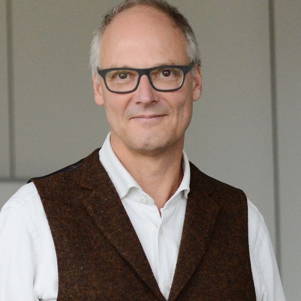 Porträtfoto von Prof. Dr. Arne Manzeschke. Älterer Mann mit Brille, grau weißen Haaren und braunen Augen.