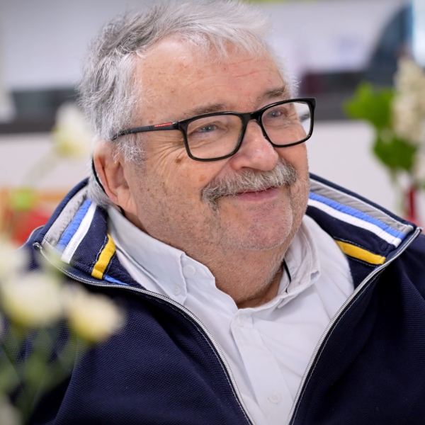 Porträtfoto von Gerhard Schumacher. Älterer Mann mit weißen Haaren und Brille lächelt