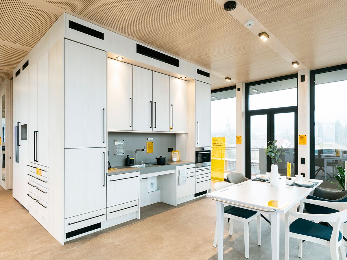Küchenzeile mit hellen Fronten und Esstisch in der Musterwohnung