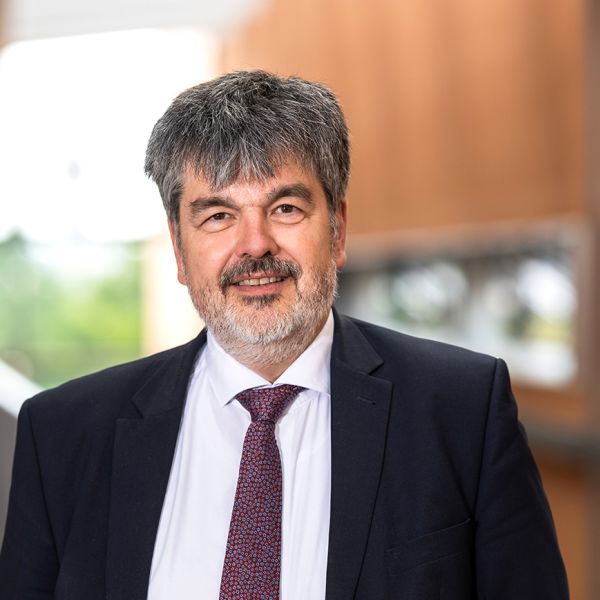 Porträtfoto von Prof. Dr. Dietmar Wolff. Älterer Mann mit Bart, grau weißen kurzen Haaren und braunen Augen im Anzug.